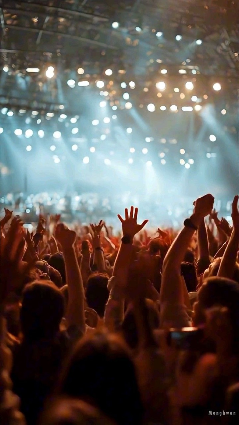 Crowd with hands up under concert lighting